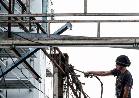 Young welder on scaffolding for dismantled the roof of factory の写真素材