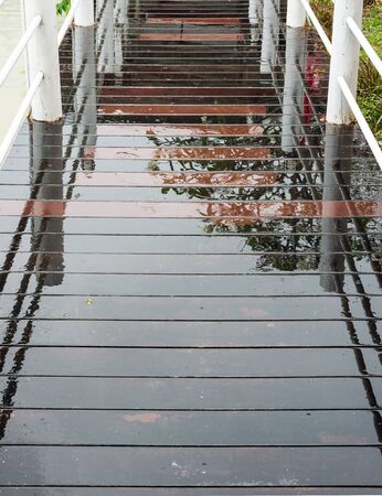 Wet wooden bridge over the small pond.の写真素材