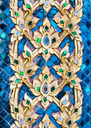 Golden flower stucco in traditional Thai style on the temple wall.の写真素材