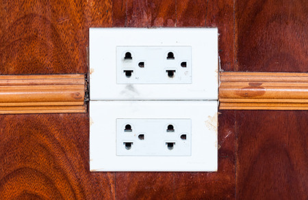 Dirty white outlet on the wooden wall of living room.の写真素材