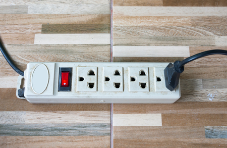 Old power strip on the wooden tile of urban house.