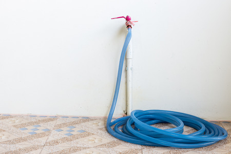 Old watering hose near the wall house.の写真素材