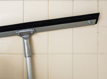 Long squeegee with matal handle near the wall of storage room.の写真素材