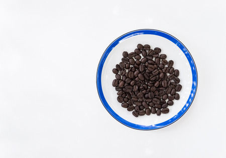 Dark roast coffee beans in the white plateの写真素材