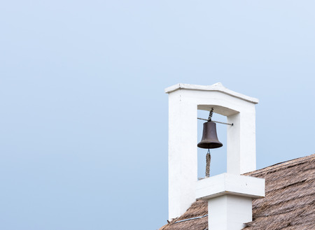 Small brass bell on the roof countryside house.の写真素材