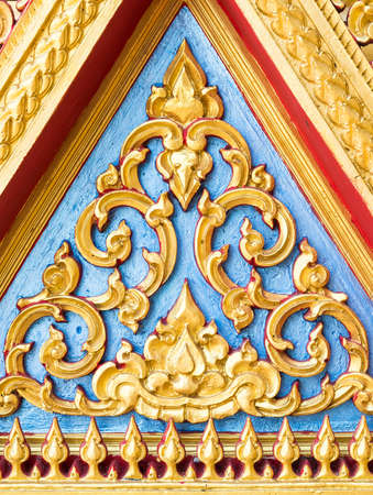 Golden stucco pattern on the triangle gable of Thai church.の写真素材