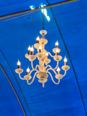 Old chandelier is hanging on the ceiling of large tent.の写真素材