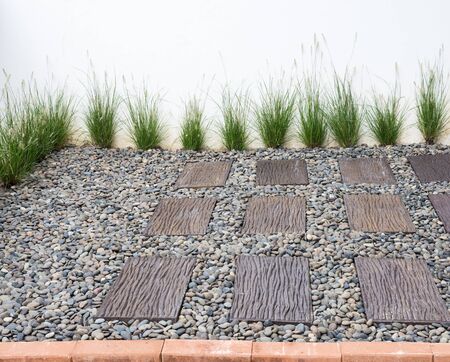 Small garden with the brick path and pebbles ground beside the white wall.の写真素材