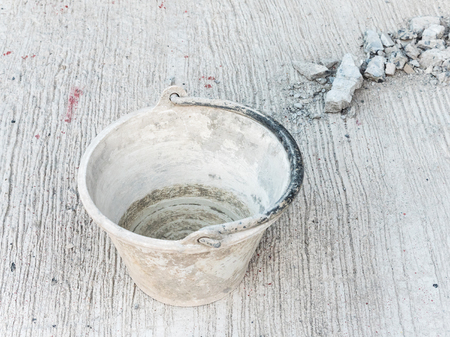 Dirty plastic bucket on the cement floor of the construction site.の写真素材