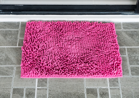 Soft doormat with the pink color on in front of the house door.の写真素材