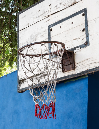 Old basketball hoop with the rusty on the blue wall of the public park.の写真素材