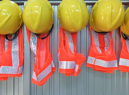 New helmet and jacket set is hanging on the office wall for foreman use in the construction site.の写真素材