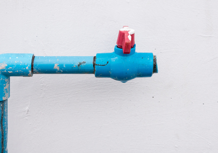 Water PVC pipe with the red plastic valve which broken from the installation near the house wall.