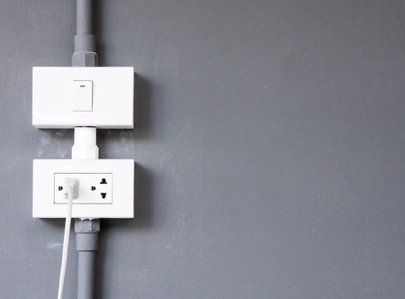 White electrical outlet with the wire and light bulb switch on the house wall.(copy space)
