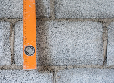 Dirty level ruler is hanging near the brick wall after measure in the unfinished house.の写真素材