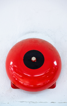 Fire alarm bell on the white concrete wall of the office building.の写真素材