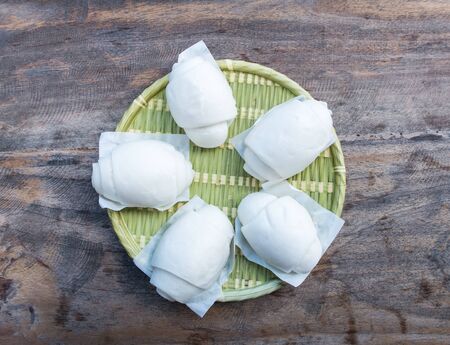 Steamed bun on the weave bamboo dish which on the wooden table of the Chinese restaurant.の写真素材
