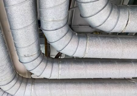 Metal pipe row is hanging along the ceiling for ventilation system in the large hospital.の写真素材