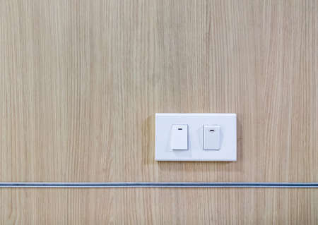 Modern light switch (plastic frame) is turned on and turned off on the veneer wall of the meeting room in the home office.の写真素材