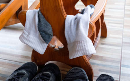 Dirty used socks after jogging are hanging for dry under the wooden table near the running shoe.の写真素材