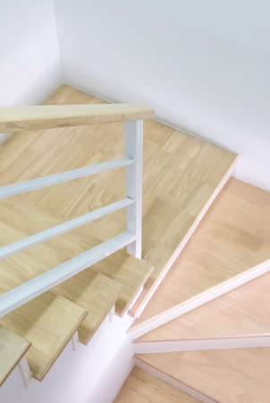 Modern curved wooden staircase with the white metal handrail in the townhouse, clean and hygienic...