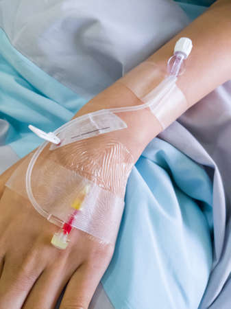 The piercing needle for giving saline solution to patients on the back of the hand of Asian women patients, inpatient rooms of the city hospitals, above view with the copy space.の写真素材