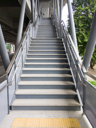 The empty modern staircase with the metal railing for entrance to the commuter train station in the...