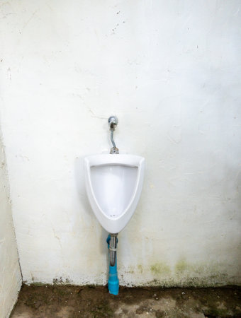 The dirty urinal of the open air toilet near the white wall in the local restaurant, front view with the copy space.の写真素材