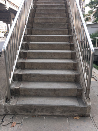 The concrete staircase of the overpass bridge near the junction in the city, stainless steel railing along the way, front view with the copy space.の写真素材