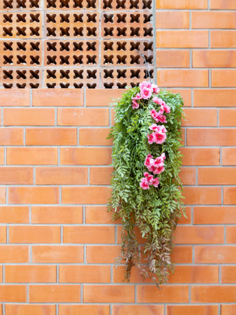The artificial flower is hanging on the brick wall decorated in the coffee shop, front view for the background.の写真素材