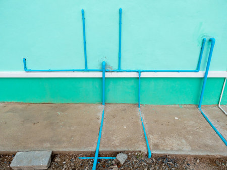 PVC drain pipe connected behind a residential house for bathroom plumbing system installation, showing modern sanitation work and clean water drainage concept.の写真素材
