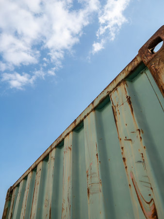 Low angle view of a weathered and retired green shipping container with rusted texture under a...