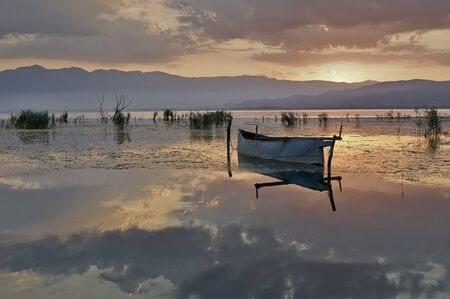 Fishing boat in lake at rising sunの写真素材