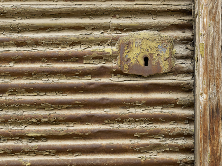 Key hole on old rusted metal shutter and wooden frameの写真素材
