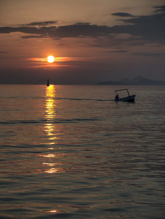 Silhouette of Fisherman at sunset returns homeの写真素材