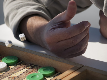 Close-up of person's hand throwing dice playing backgammon