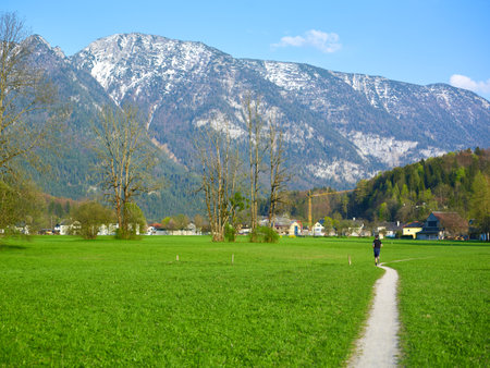 An athlete runs along the road through a field.の写真素材