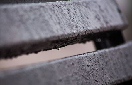 Water drops on the wet gray bench in rainy weather