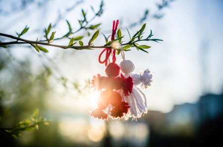 Red and white beautiful martisor hanging on the branches of the tree. Martenitsa beginning of spring...