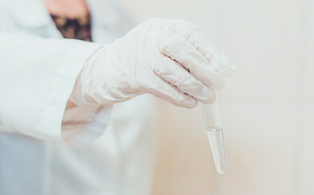 Scientist holding a test tube with blood sample in laboratory, close up