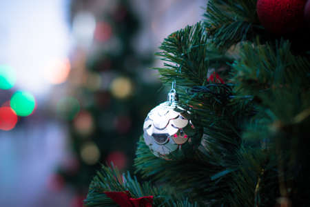 Vivid Christmas decorations on the pine tree branch closeup. Blurred background and shiny Christmas lights. Bokeh. Vivid ball sphereの写真素材