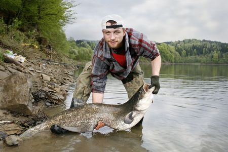 A happy fisherman presenting his fishing trophy caught in a Polish lake - catfish (Silurus glanis)の写真素材