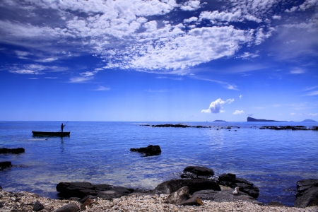 Fisherman on the sea near the black lava shore の写真素材