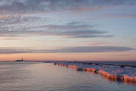 Sea on sunset with lighthouse in winterの写真素材