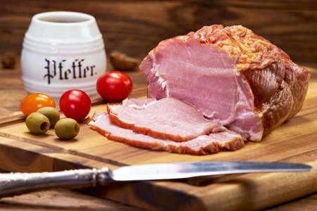 Tasty raw ham on a kitchen board, in the background a dish with pepperの写真素材