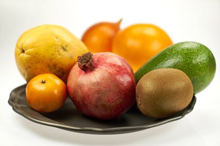 Exotic fruits - pomegranate, papaya, mango and others on metal plates, on a white background