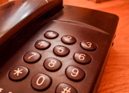 old landline phone with buttons on a yellow wooden background.