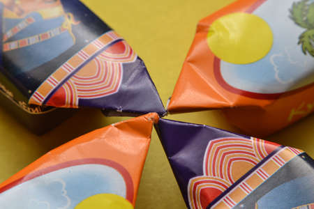 four chocolate candies on a yellow table.