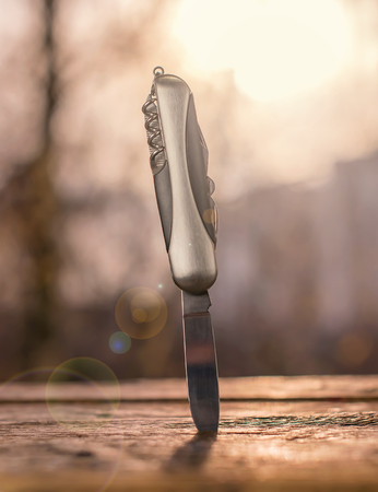 knife stuck in a wooden board on the background of the rays of the setting sunの写真素材