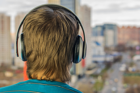 guy in headphones are an audiophile, listening to music in big headphones on the background of cityの写真素材